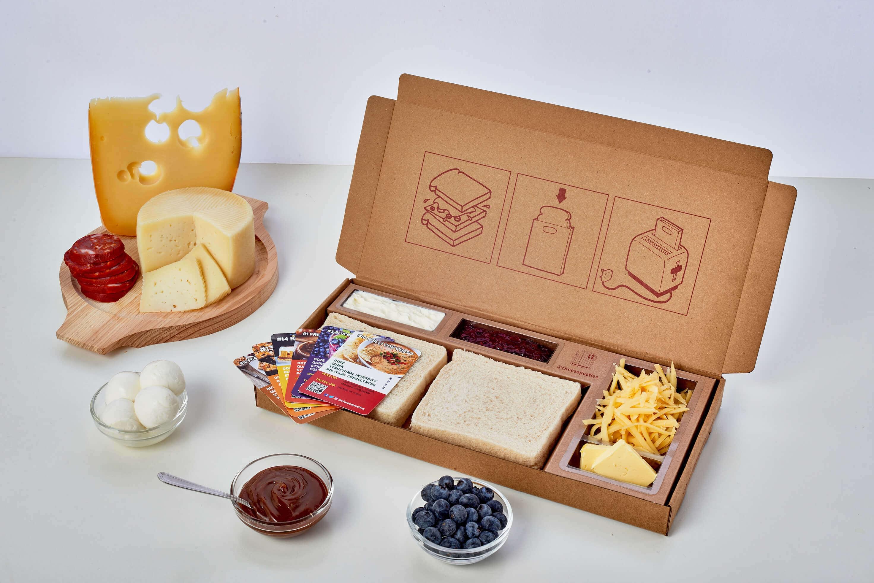 An open Cheese Posties box with bread, cheese, fillings and collectable Toast Trumps cards